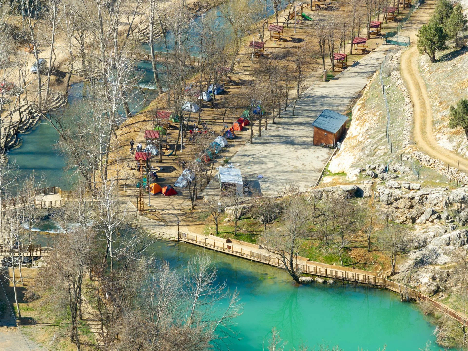 Camp mit bunten Zelten am türkisen Flussufer.